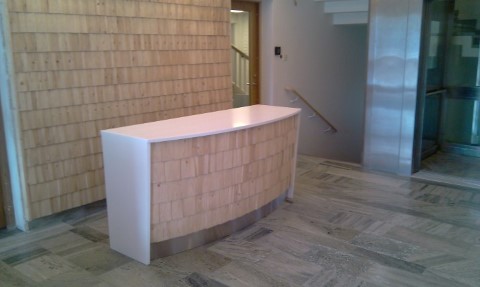 Dekorvägg och receptionsdisk med vit komposit och takspån av gran